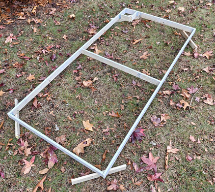 A wooden flat, laid out in the yard; it has been painted recently, and the paint is drying.