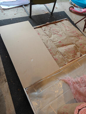 frame with insulation and MDF one wooden flat, on the floor, with fiberglass insulation affixed to the inside. An MDF panel has been affixed to the top end of the frame.