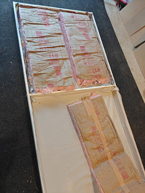 frame with insulation one 3-foot wooden flat, on the floor, with fiberglass insulation affixed to the inside.